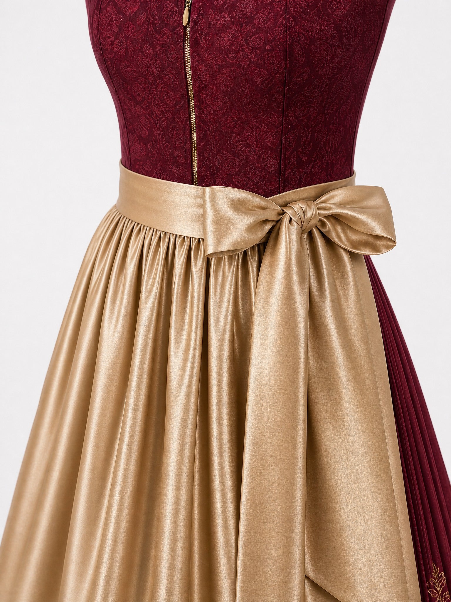 Dirndl Pia in Cranberryrot mit Antikgold Schürze - Detailansicht Taille und Schleife
